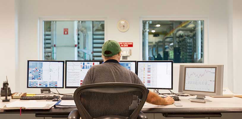 Man looking at multiple computer screens in factory setting