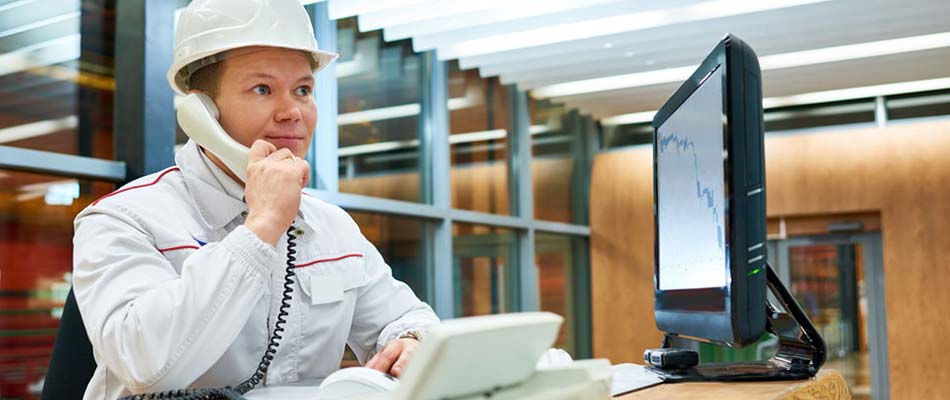 Man sitting at desk, on phone, in front of computer