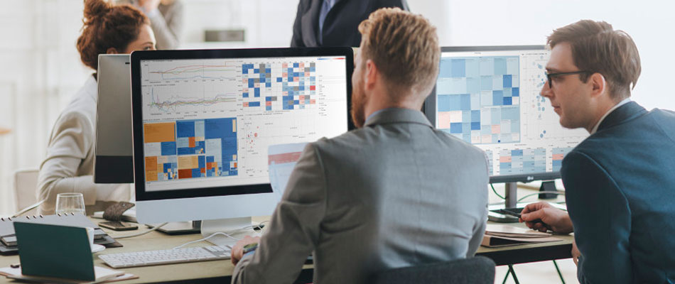 Two men sitting at desks looking at computers displaying data analytics dashboards