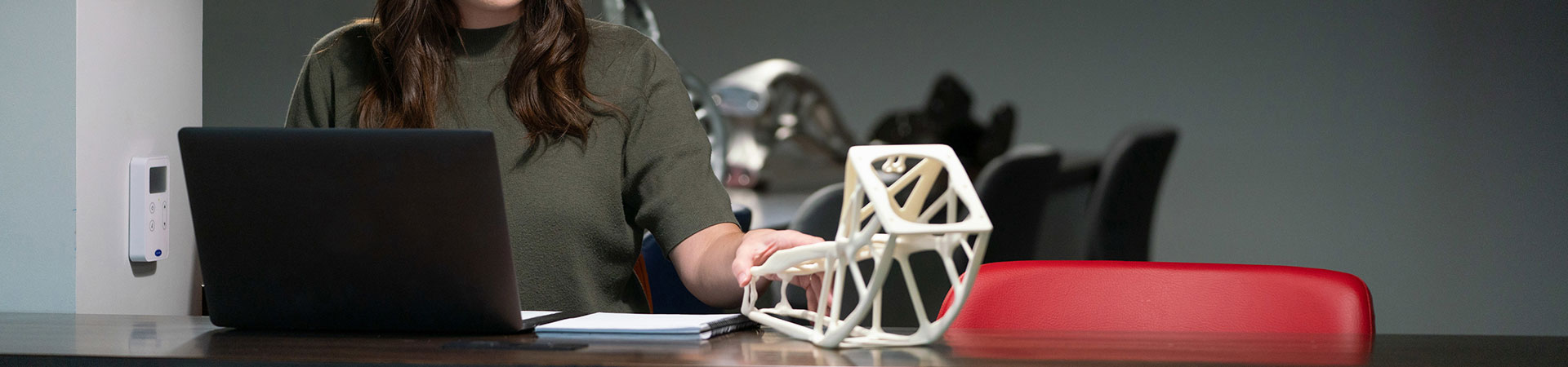 Frau an Computer, die ein 3D-gedrucktes Teil anfasst 