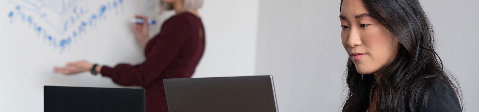 Frau in einer Besprechung, die auf einen Laptop schaut